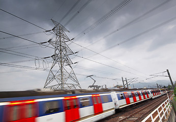 Image showing passenger trains in motion and power tower on background