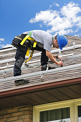 Image showing Man working on roof installing rails for solar panels