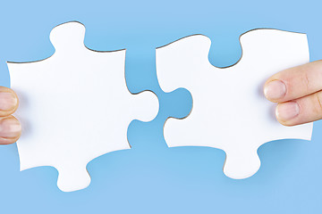 Image showing Fingers holding jigsaw puzzle pieces