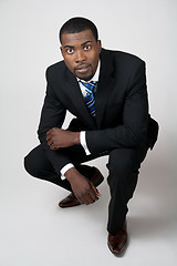 Image showing Business man in black suit squatting