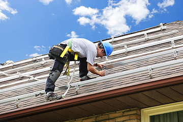 Image showing Man working on roof installing rails for solar panels