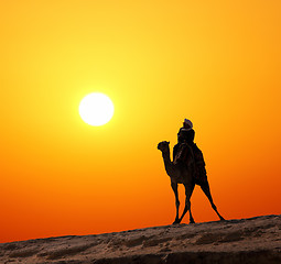 Image showing bedouin on camel silhouette against sunrise