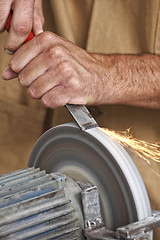 Image showing manual worker sharp his tool