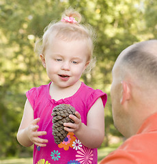 Image showing Young Girl Holding Pinecone with Her Dad in Park