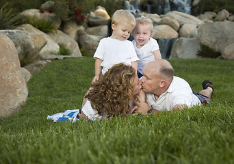 Image showing Affectionate Couple Kiss as Cute Twins Look On