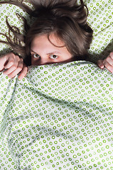 Image showing Portrait of a young girl hiding under blanket