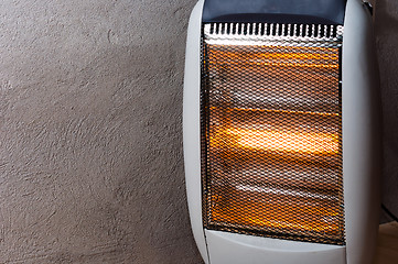 Image showing A halogen or electric heater against concrete wall