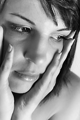 Image showing young woman holding her face with hands in black and white