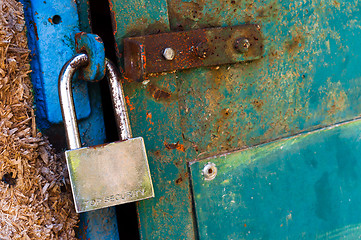 Image showing Rusty old padlock on metal door