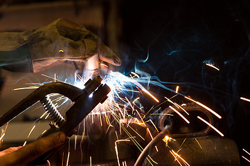 Image showing worker welding steel with white sparks