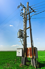 Image showing Power lines against green field and blue sky