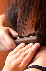 Image showing Girl using iron on her hair