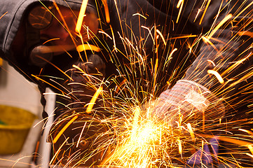 Image showing Worker cutting metal with many sharp sparks
