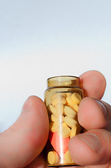 Image showing Hand holding medicine bottle full of pills