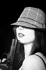 Image showing Beautiful young girl in hat holding pistol in black and white