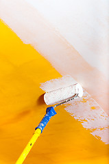 Image showing White paint over yellow wall with painting rod