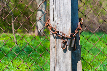 Image showing Old padlock with chains onb wooden fence