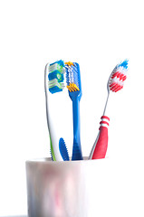 Image showing colorful toothbrushes in a glass over white