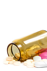 Image showing Medicine bottle with purple and yellow pills against white isola