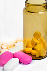 Image showing Medicine bottle with purple and yellow pills against white isola