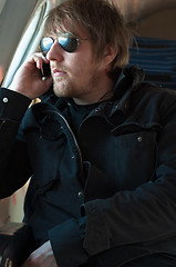 Image showing Portrait of a young man holding phone in a seat of an airplane