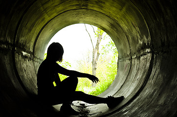 Image showing Silhouette of a young girl smoking in sewer pipe