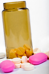 Image showing Medicine bottle with purple and yellow pills against white isola