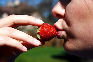 Image showing face of the woman eating a strawberry