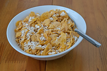 Image showing White bowl with a spoon, corn and oats flakes