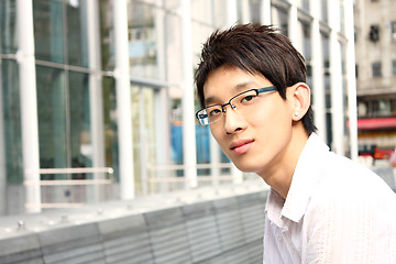 Image showing businessman sitting on a bench in front of an office building 