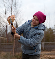 Image showing Girl cuts firewood with an ax