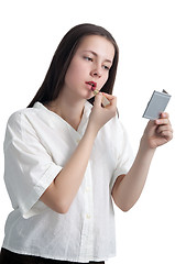 Image showing A young girl with her hair applying lipstick