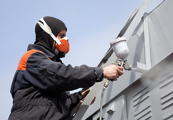 Image showing A commercial painter on the stairs spray painting a steel exteri