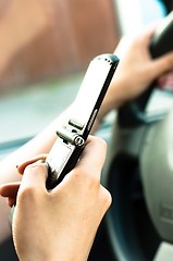 Image showing A phone in the hand os a woman who is driveing 