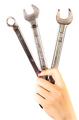 Image showing Hand of a girl holding several spanners 