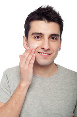 Image showing Young man applying cream lotion