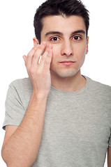 Image showing Young man applying eye cream