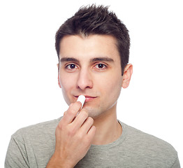 Image showing Young man applying lip balm
