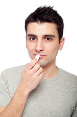 Image showing Young man applying lip balm