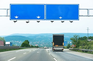 Image showing Big blue sign on highway with truck and car