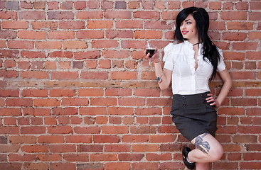 Image showing Black-haired tattooed girl with a glass of red wine