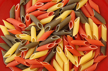 Image showing penne tricolore pasta on red background