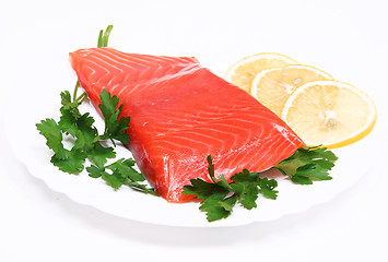 Image showing Salmon steak with lemon slices and parsley on white plate