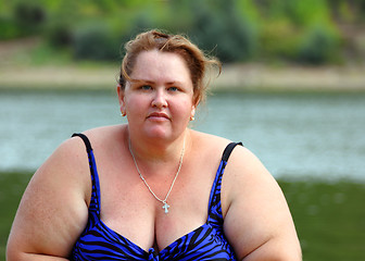 Image showing plump woman sitting near river