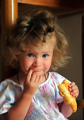 Image showing little girl eating croissant
