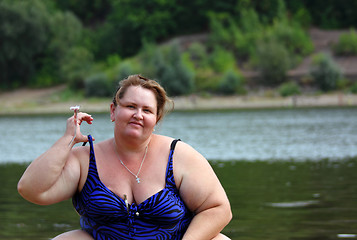 Image showing plump woman sitting near river