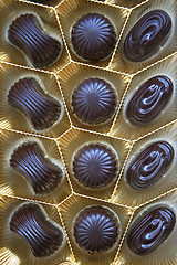 Image showing Delicious dark chocolate sweets in box as background
