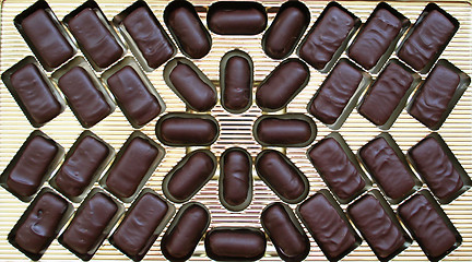 Image showing Delicious dark chocolate sweets in golden box as background