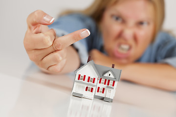 Image showing Angry Woman Flipping The Bird Behind Model Home on White