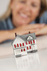 Image showing Smiling Woman Behind Model House on a White Surface